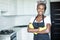 Smiling african american housewife in apron with arms crossed cleaning at home