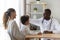 Smiling african american male doctor stroking head of little patient.