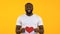 Smiling African-American man holding paper heart, charity and kindness, slow mo