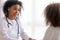 Smiling African American pediatrician doctor talking to patient child