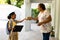 Smiling african american scout girl in uniform delivering package to senior woman at home