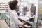 Smiling African American woman clinical pharmacist typing on computer keyboard, while standing behind the counter of