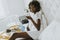 Smiling african american woman having a relaxing breakfast in be