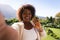 Smiling african american woman on sunny balcony of country home making video call, waving