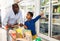 Smiling African family of father and tween son shopping together in supermarket