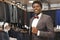 Smiling african man posing in boutique in grey suit.