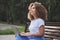 Smiling African modern woman with curly hair thinking working remotely online use laptop at park