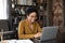 Smiling African woman sit at desk working on laptop