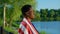 Smiling Afro-American man with American flag on shoulders looks at sunrise