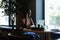 Smiling afro american woman sitting on table pointing finger up and working in coffee house side view. Black girl