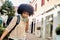 Smiling afro haired woman with headphones walking in city. Portrait of happy latina woman