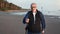 Smiling aged 70s man Scandinavian walking stick healthy lifestyle outdoor sport activity sea beach