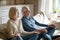 Smiling aged couple meditate on couch at home