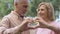 Smiling aged couple showing heart sign, love symbol, happy marriage, affection