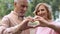 Smiling aged couple showing heart sign, love symbol, happy marriage, affection