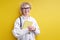 Smiling aged woman holding book in hands, wearing eyeglasses, confident teacher