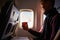 Smiling airline passenger with a paper cup of coffee looking ahead in airplane window. Man drinks tea onboard. Male