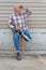 Smiling amputee man sitting on a stool, prosthetic leg crossed, shading eyes looking up