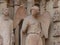 Smiling angel with beguiling smile giving a fist pump on the entrance to Notre-Dame de Reims Cathedral in France