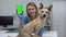 Smiling animal clinic doctor showing green screen phone, online pet checkup app