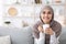 Smiling Arab Woman In Hijab Relaxing On Couch With Coffee, Enjoying Weekend