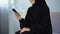 Smiling arab woman reading smartphone message, online communication, chatting