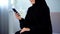 Smiling arab woman reading smartphone message, online communication, chatting