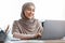 Smiling Arabic Female Entrepreneur In Hijab Using Laptop In Office