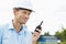 Smiling architect holding walkie-talkie at construction site