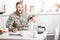 smiling army soldier sitting at kitchen table and