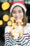 Smiling asia woman wear santa hat holding party string lights wi