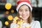 Smiling asia woman wear santa hat holding party string lights wi