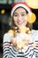 Smiling asia woman wear santa hat holding party string lights wi