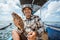 smiling Asian angler holding a grouper on small fishing boat