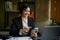 Smiling Asian businesswoman enjoys chatting with someone while sitting at her desk