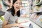 Smiling asian child girl wearing glasses sitting reading a book on the floor,teenage student feel enjoying study in library,happy