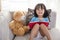 Smiling Asian Chinese little girl reading book with teddy bear