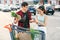 Smiling asian couple standing near shopping cart,man holds pineapple and cheerful woman counts the banknotes