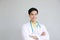 Smiling asian doctor man in Gown uniform and hand holding stethoscope is smart portrait on white wall.