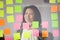 Smiling Asian female employee write ideas on sticky notes
