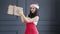 Smiling Asian female Santa Claus holding big carton gift box with bow at studio in gray background