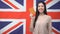 Smiling Asian girl holding passport against British flag background, citizenship