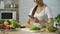 Smiling Asian girl watching video recipe on smartphone before cooking dinner