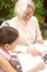 Smiling asian grandmother is drawing outside with granddaughter. Casual, outdoors