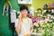 Smiling asian male florist calling on smartphone at flower shop.