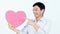 Smiling Asian man holding a pink heart