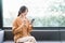 Smiling asian woman with coffee using smartphone in a cozy corner.