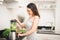 Smiling asian woman making smoothie with fresh vegetables in the