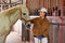Smiling Asian woman stable keeper stroking white purebred horse