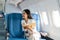 Smiling Asian woman taking notes of information and sitting in airplane, Business traveling and technology concept